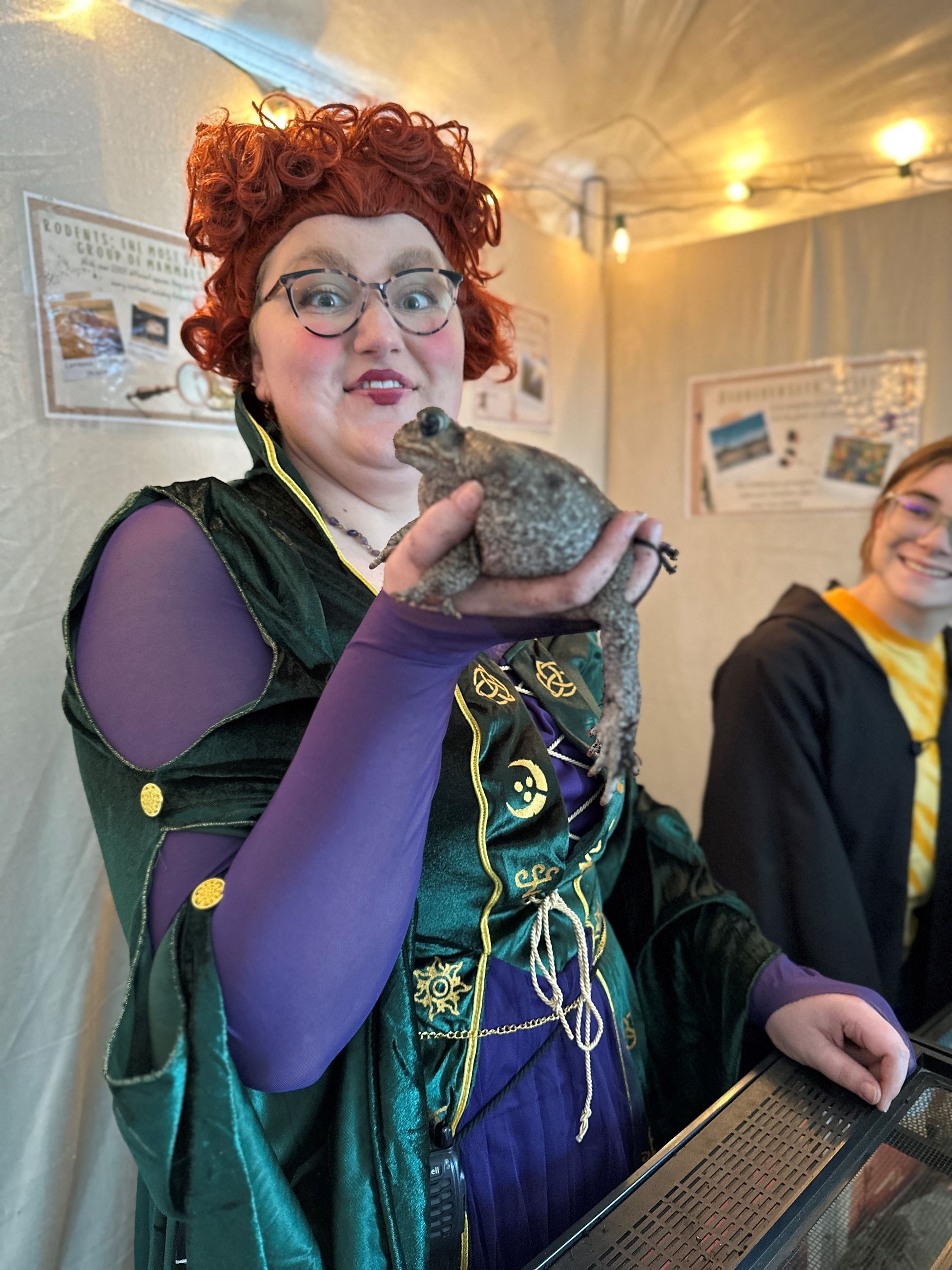 A young white woman dressed as a witch holding a toad